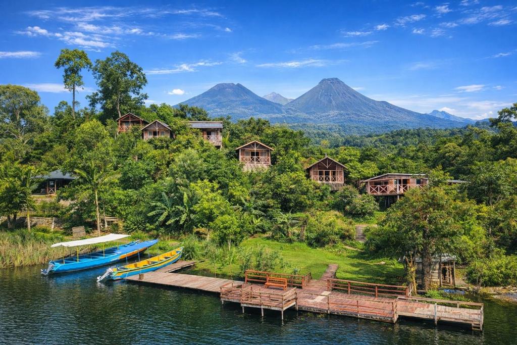 a resort with boats on the water and mountains at Mutanda Eco Community Center in Kisoro
