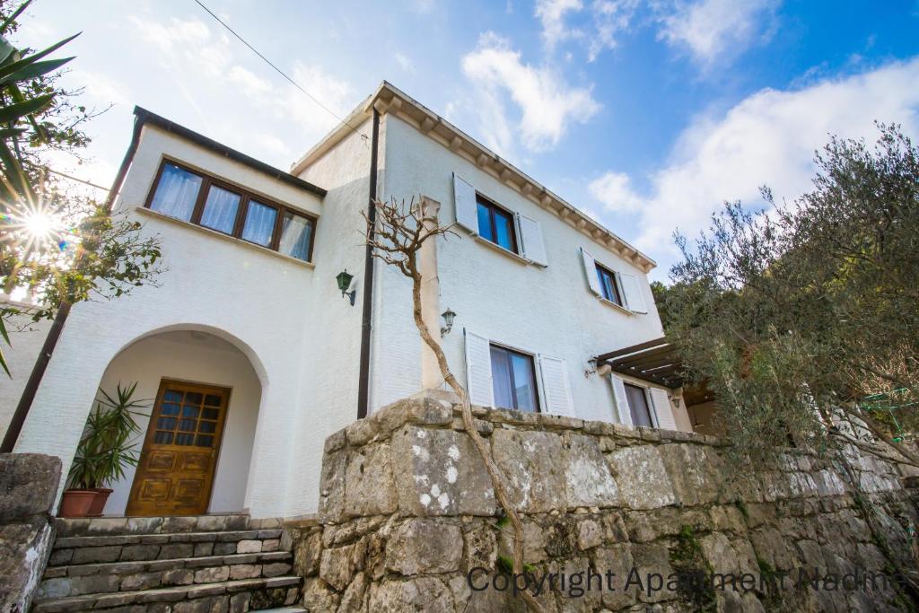 a white house with a tree on a stone wall at Apartments Nadine Mljet Komfort mit Meerblick in Okuklje