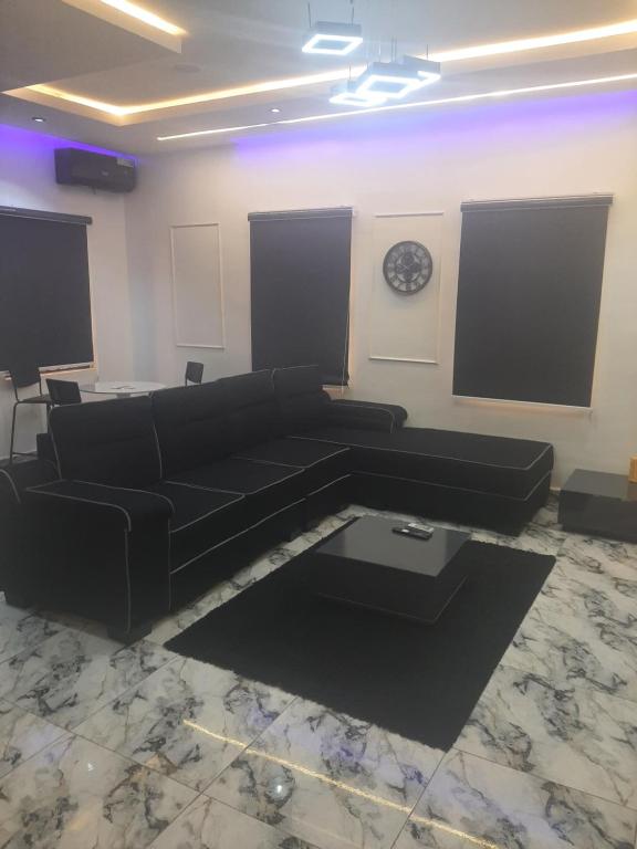 a living room with a black couch and a clock at Jasper luxury homes in Abuja