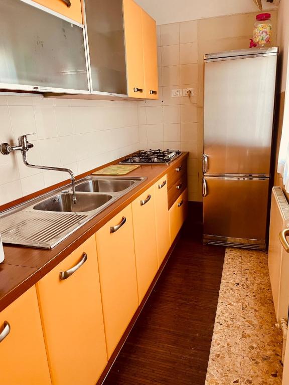 a kitchen with yellow cabinets and a stainless steel refrigerator at A casa di Rita in Udine