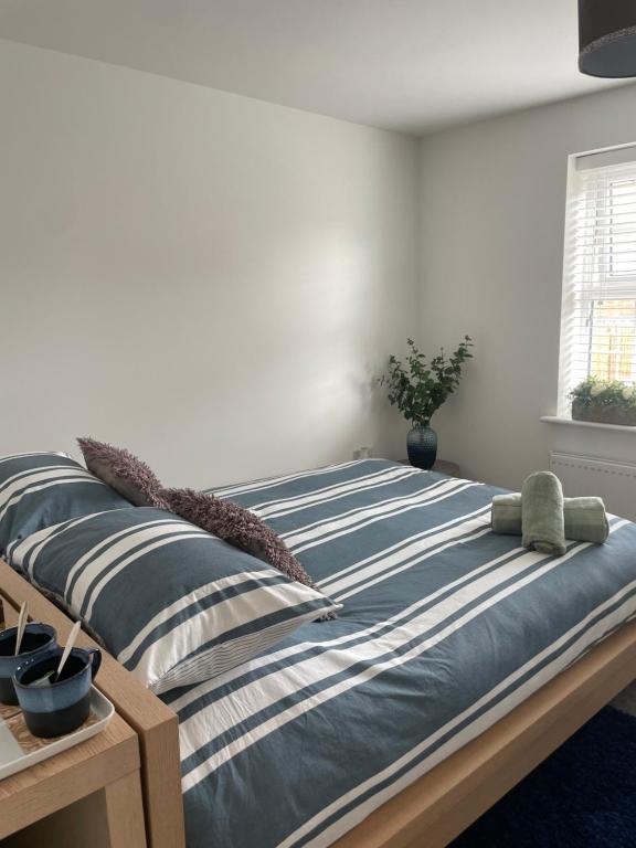 a bedroom with a bed with blue and white stripes at Rushes View Homestay in Market Harborough