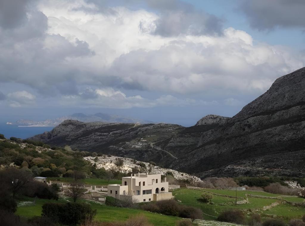a house in a field with mountains in the background at Pera Horio House in Apérathos