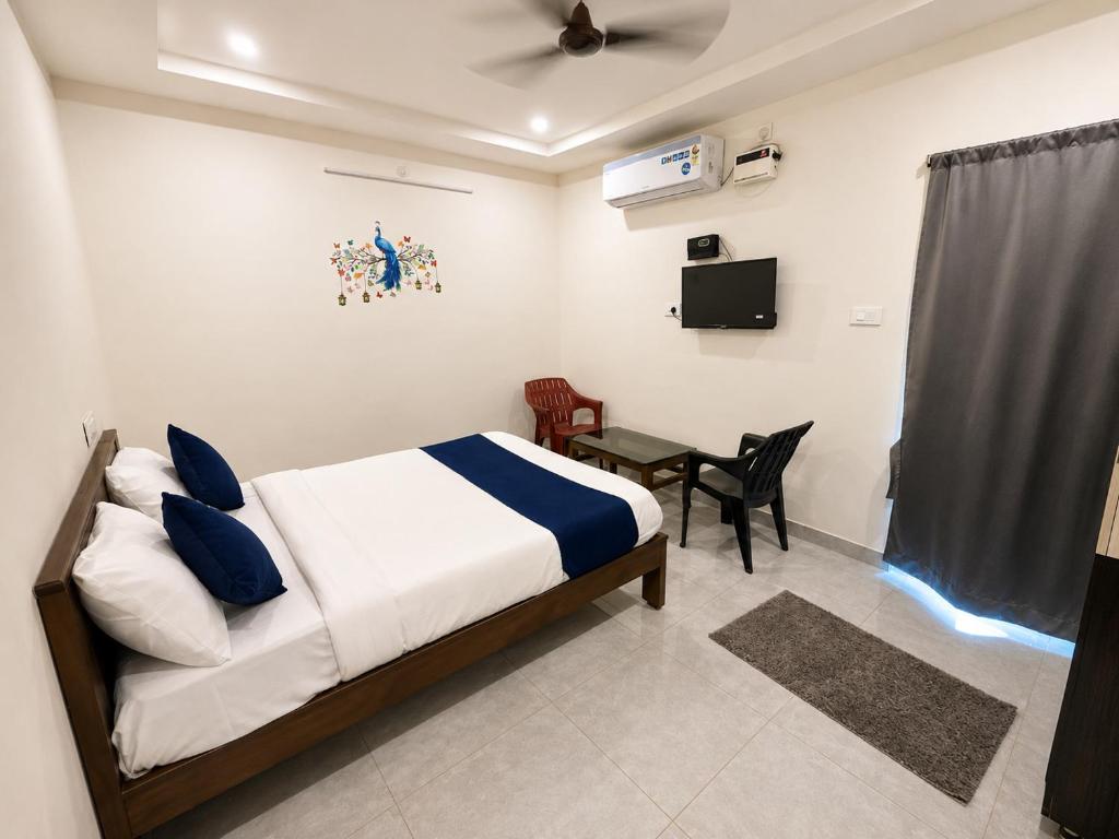 a bedroom with a bed and a table and a tv at MGR RESIDENCY in Srikalahasti