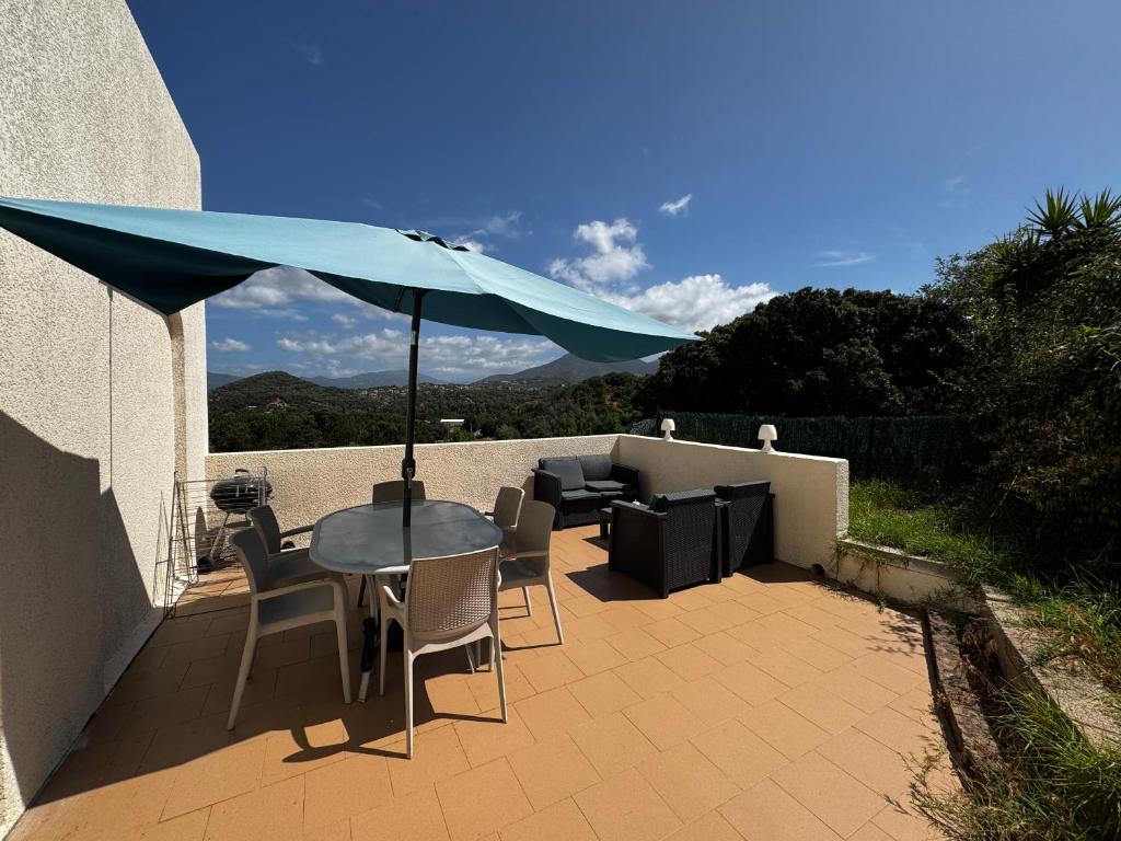 ein Tisch und Stühle mit einem Sonnenschirm auf einer Terrasse in der Unterkunft U refuggiu in Porticcio
