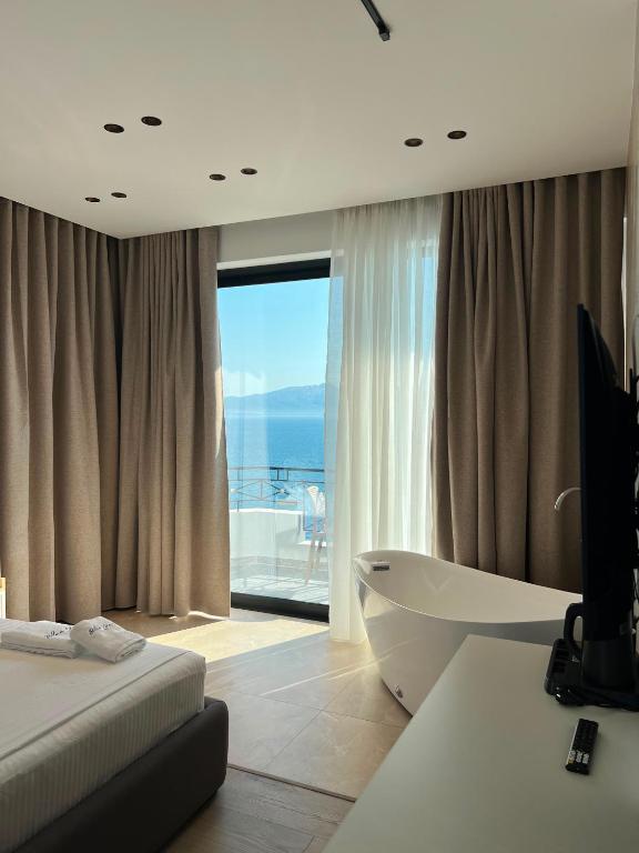 a bedroom with a tub and a view of the ocean at Blue Waves Hotel & Suites in Sarandë