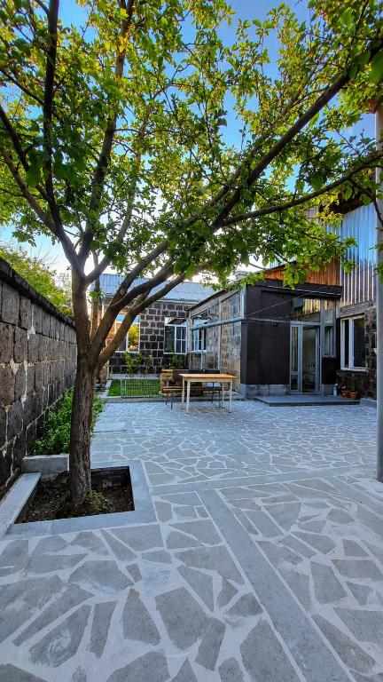a tree in the middle of a courtyard with a bench at Guest House David's B&B in Gyumri
