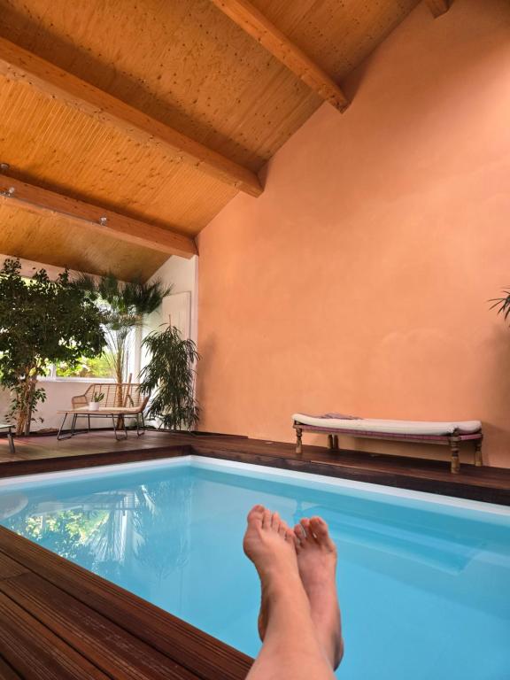 a person with their feet on the edge of a swimming pool at Aux quatre coins du monde in Champvoux