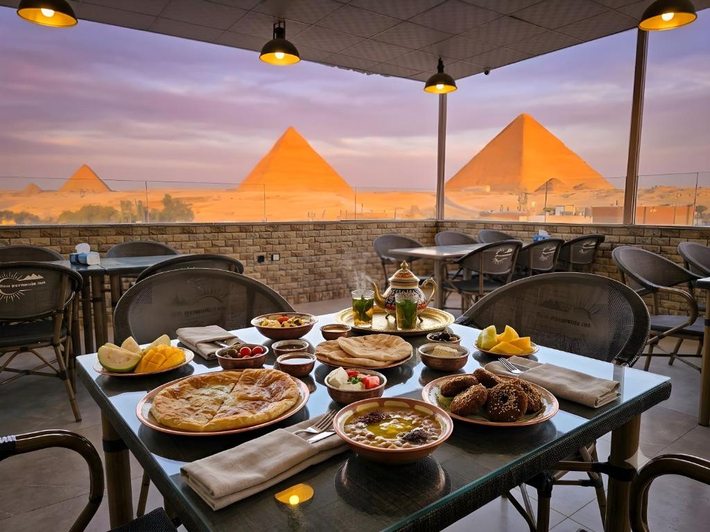 a table with food on it with pyramids in the background at nova pyramids inn in Cairo