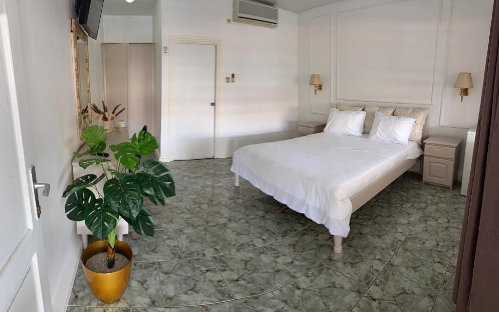 ein Schlafzimmer mit einem weißen Bett und einer Topfpflanze in der Unterkunft Zenaida in Paramaribo