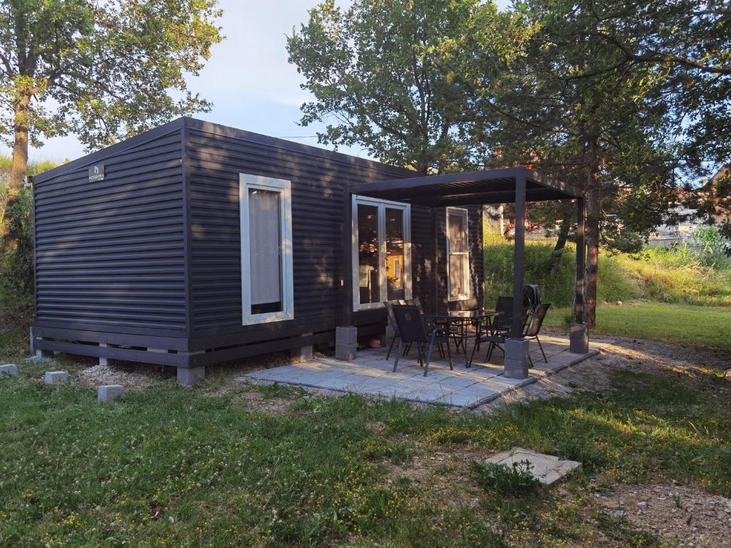 a small cabin with a table and chairs in a field at Forest house Maestral in Koper