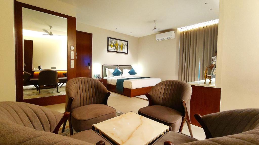 a hotel room with a bed and chairs and a mirror at Radiance Hotel in Sirsa