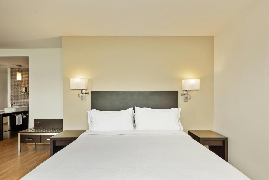 ein Schlafzimmer mit einem großen weißen Bett und ein Badezimmer in der Unterkunft Fiesta Inn Express Naucalpan in Mexiko-Stadt