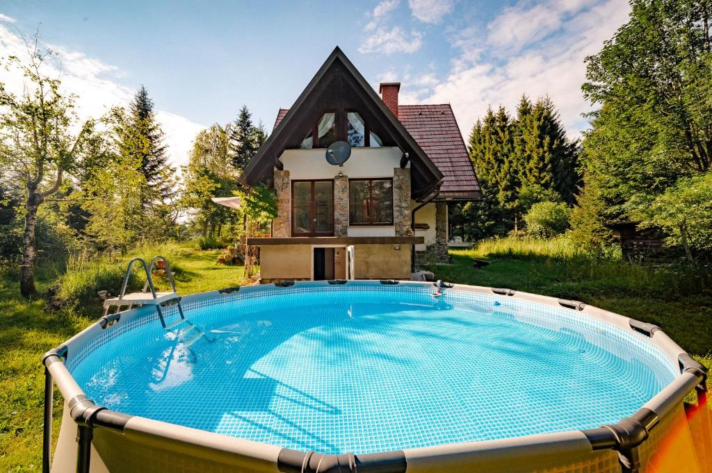 a house with a large swimming pool in front of a house at Sanjska Hiša Vojsko in Idrija