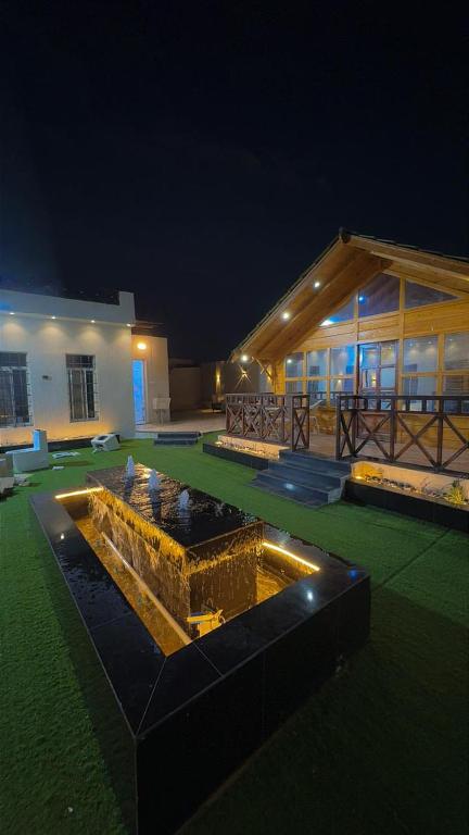 a building with a fountain in a yard at night at شاليه دار وارف in As Sayl aş Şaghīr