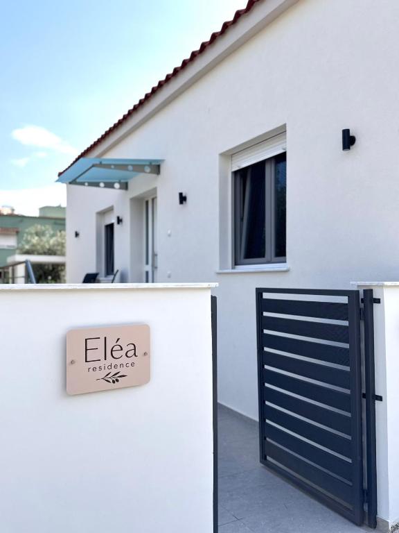ein weißes Haus mit einem Tor und einem Schild in der Unterkunft Elea residence in Elaiokhórion