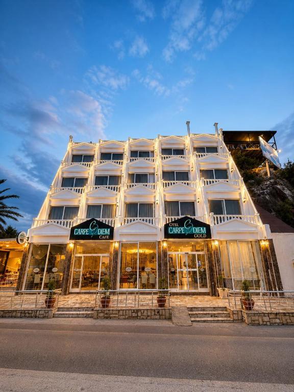 a large white building with a store front at Carpe Diem Hotel in Finike