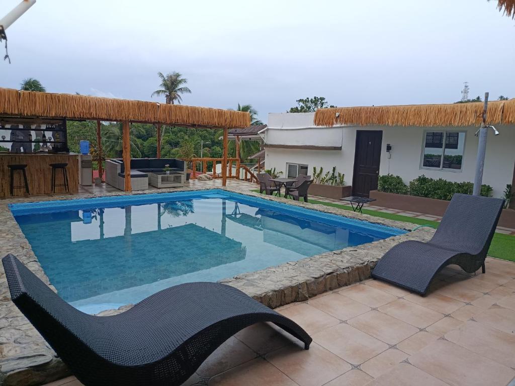 a swimming pool with two chairs and a house at V Hostel Galera in Puerto Galera