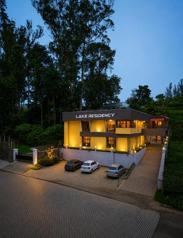 two cars parked in a parking lot in front of a building at Lake Residency Ooty in Ooty