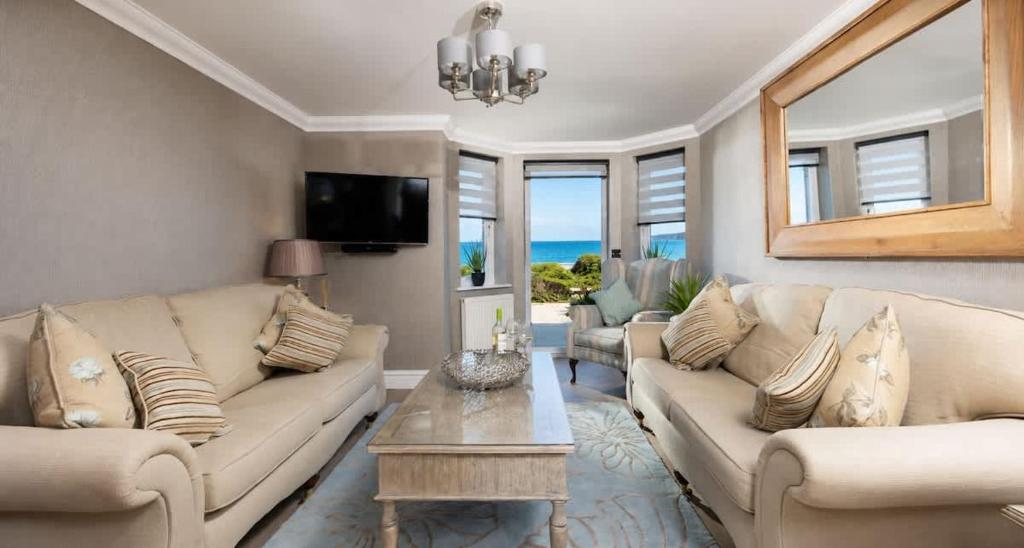 a living room with two couches and a table at Crystal View by the Sea in Carbis Bay