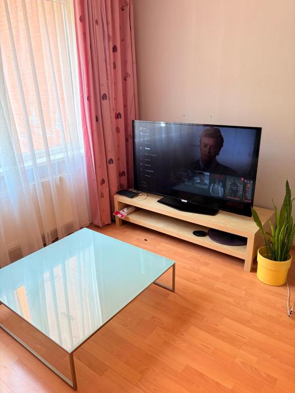 a living room with a tv and a glass coffee table at Dzirciema apartment in Riga