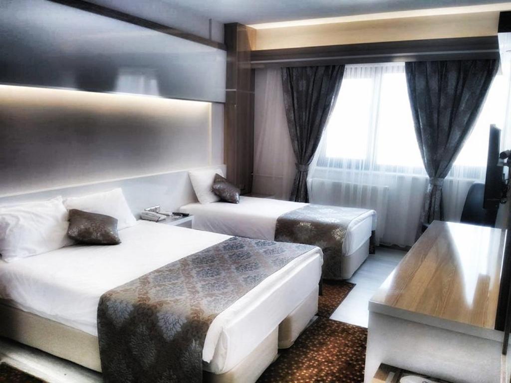 a hotel room with two beds and a couch at Napa Hotel in Denizli