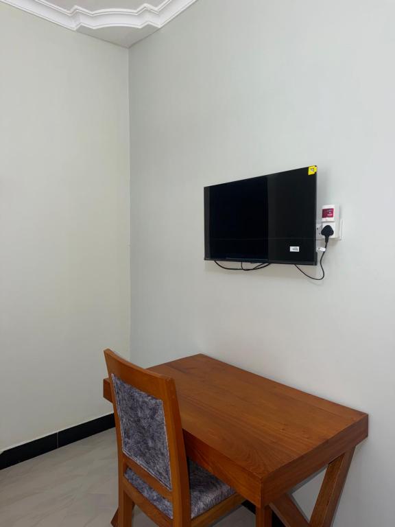 a wooden table with a television on a wall at Angels Lodge in Dar es Salaam