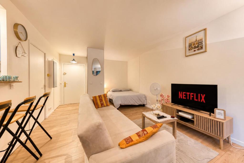 a living room with a couch and a tv at Charmant appartement proche Val Europe Disneyland paris in Torcy