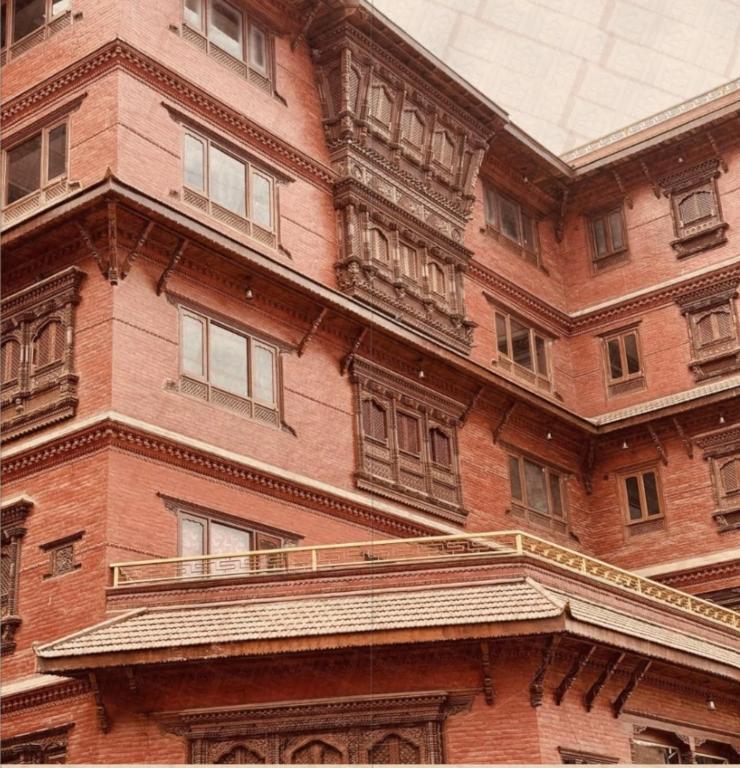 a red brick building with windows and a balcony at Hotel Dachi Kathmandu - Bhaktapur in Bhaktapur