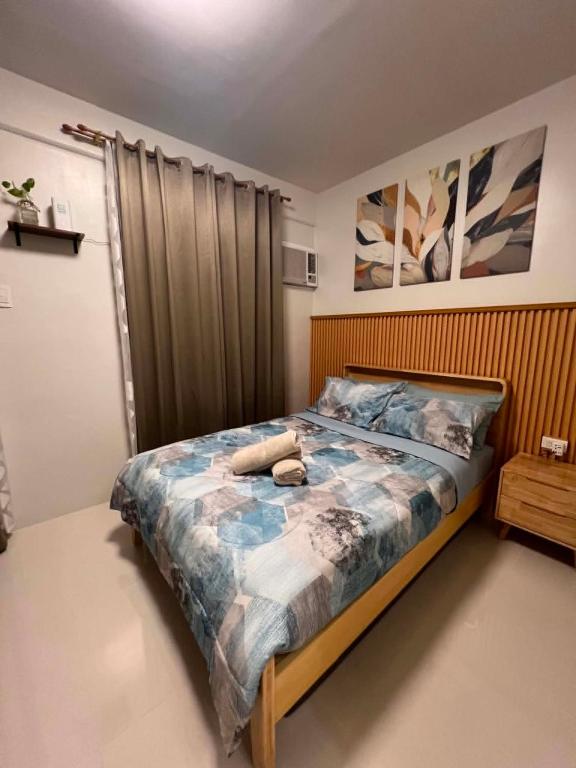 a bedroom with a bed with a wooden headboard at Cozy Crib at Royal Oceancrest Mactan in Mactan Island
