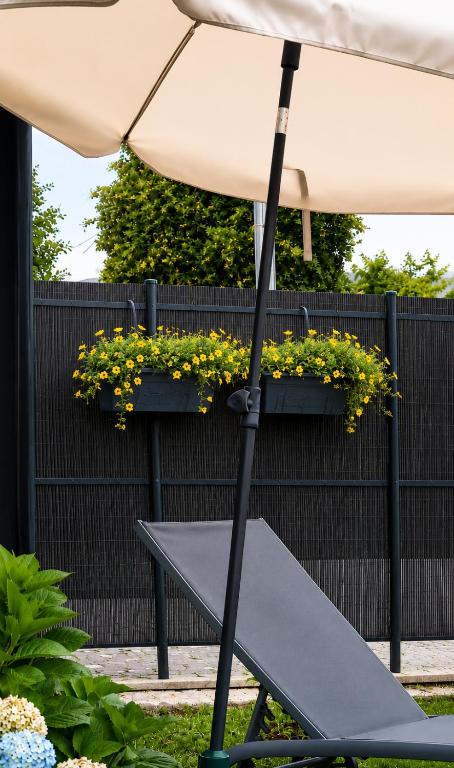 an umbrella and a bench in a garden at Jardim das Oliveiras - Suítes com Vista in Ponte de Lima