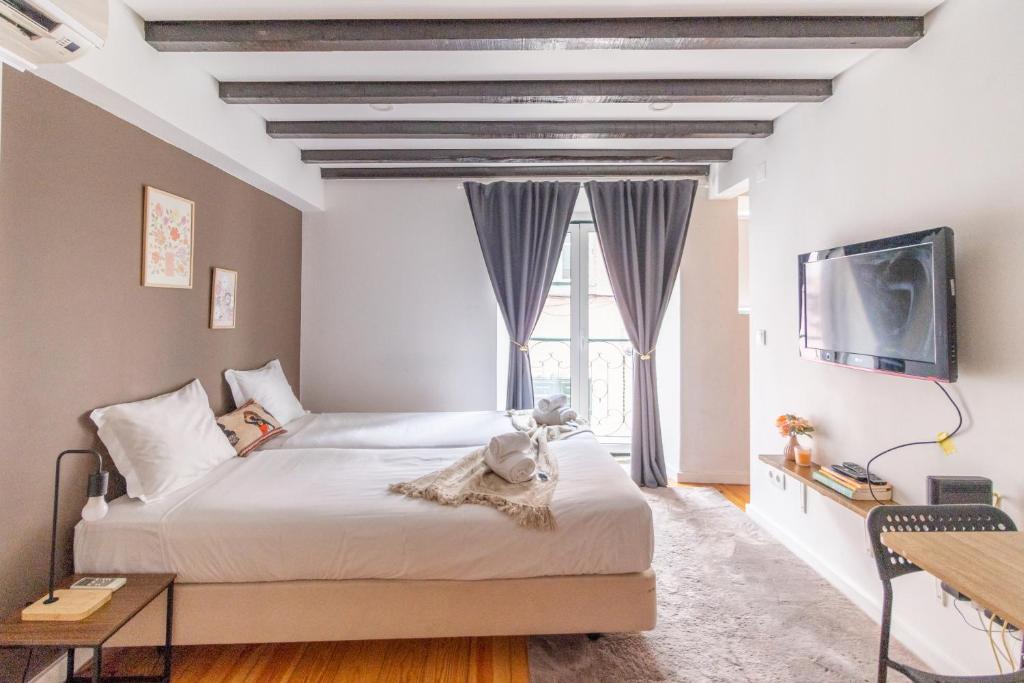 a bedroom with a large bed and a tv at Alma do Bairro in Lisbon