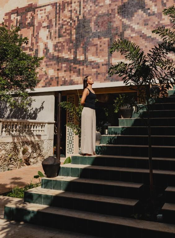 Eine Frau steht auf einer Treppe. in der Unterkunft CIGNO Mejorada Hotel Boutique in Mérida