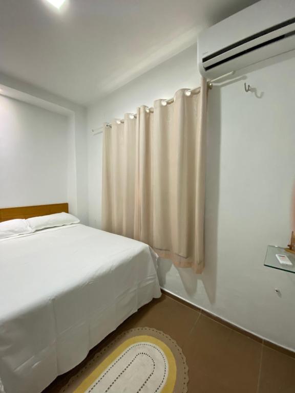 a white bedroom with a bed and a window at Green duplex cottage in Camocim in Camocim