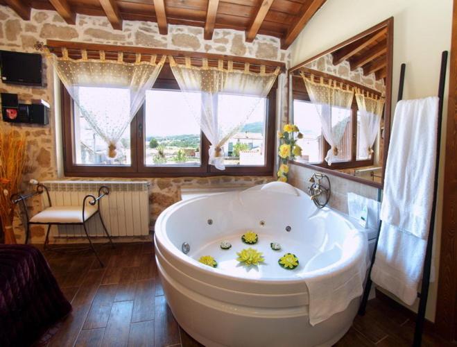 a large white tub in a bathroom with windows at CASA RURAL SANDRA in La Carrera