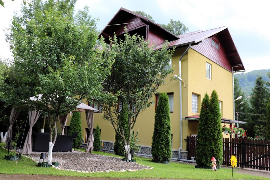 a yellow house with trees and a fence at Casa Drumetului in Comarnic