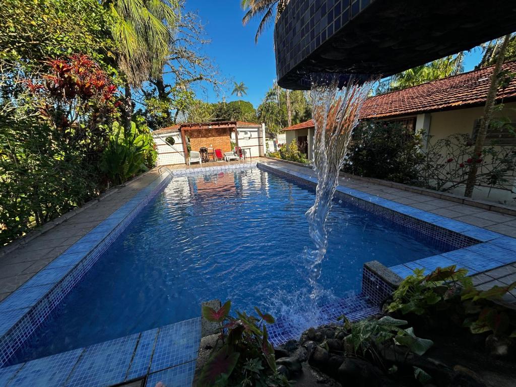 a swimming pool with a water fountain at Chacara c piscina ampla em Pedro de toledo in Pedro de Toledo