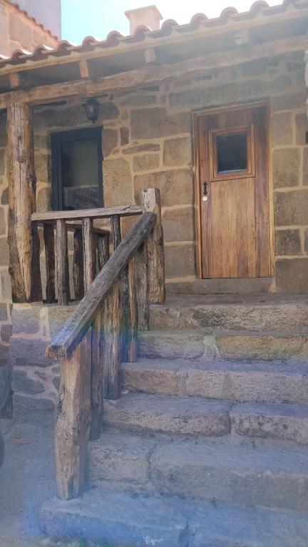 a stone house with stairs and a wooden door at Fuinhas de Amor a 2 in Fuinhas