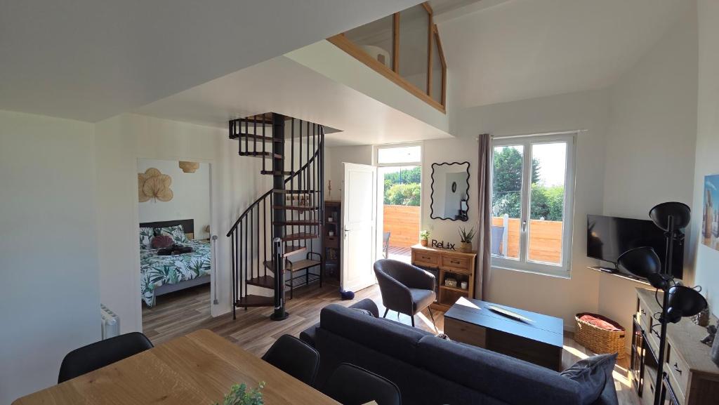 a living room with a couch and a spiral staircase at L'escale du Cap A in Barneville-Carteret