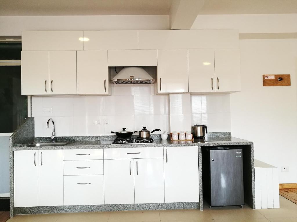 a white kitchen with white cabinets and a sink at Ananya Apartments Phase 1 in Kathmandu