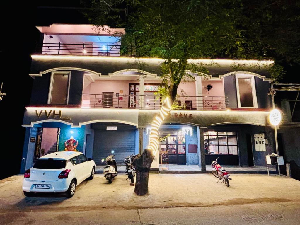 a white car parked in front of a building with motorcycles at The Loop Auroville - High-Speed WiFi & Free Parking, Near Auroville Bakery & Tanto Pizzeria, 5-Minute Drive to ECR & Auroville Beach in Auroville