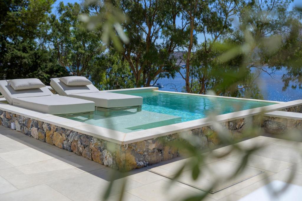 a swimming pool with two lounge chairs and a table at Vista Portolago Villas & Suites in Lakkíon