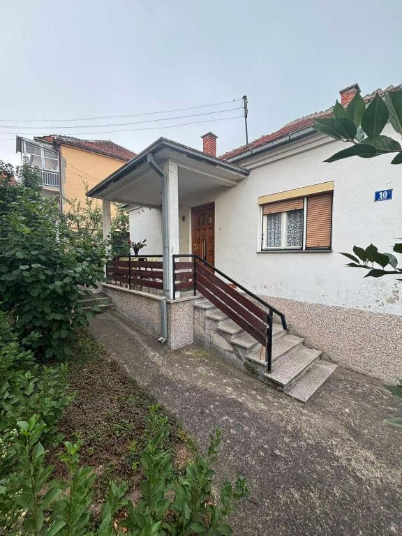a white house with a porch and stairs in front of it at Vila Vuković in Leskovac