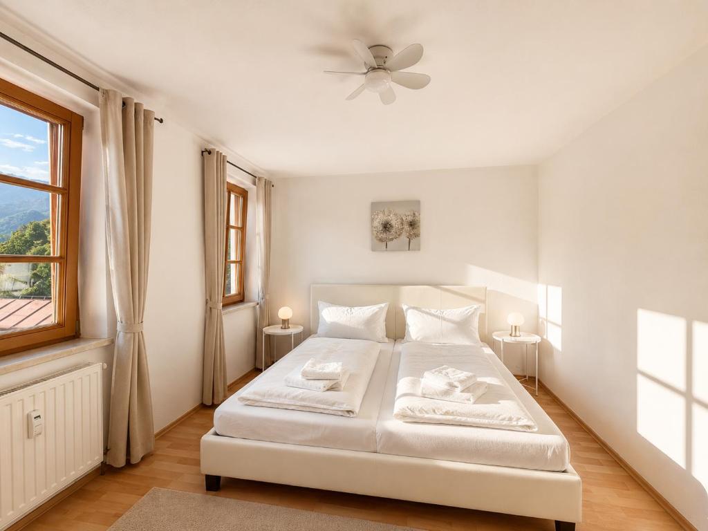 a white bedroom with a white bed and a window at KAISERLICH WOHNEN zentral und am Fluss in Bad Ischl