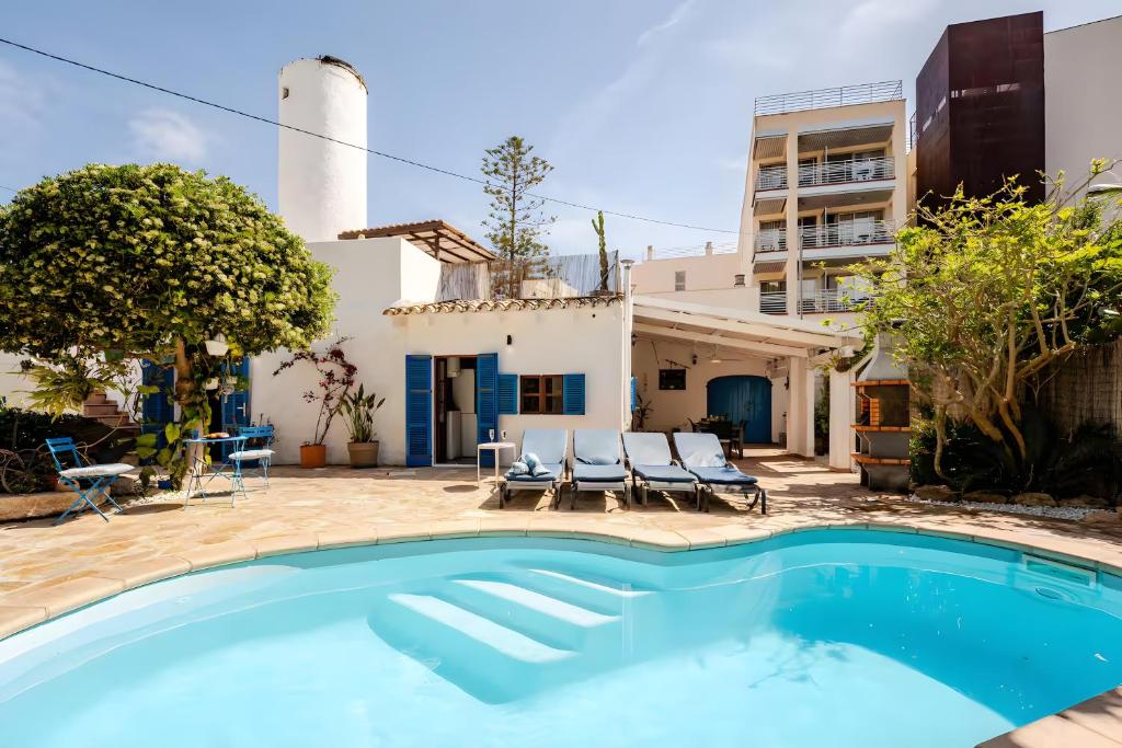 a pool in front of a house with chairs and a building at Molino Son Moll in Cala Ratjada