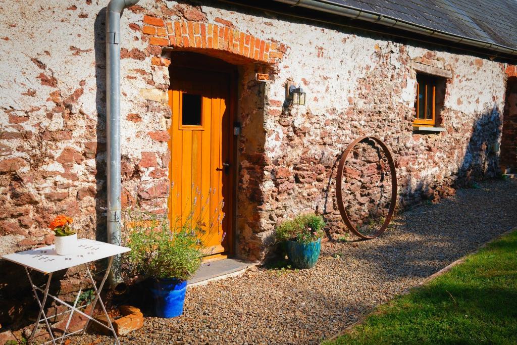 a brick building with a yellow door and a table at The Old Cowshed - B and B in Pembroke