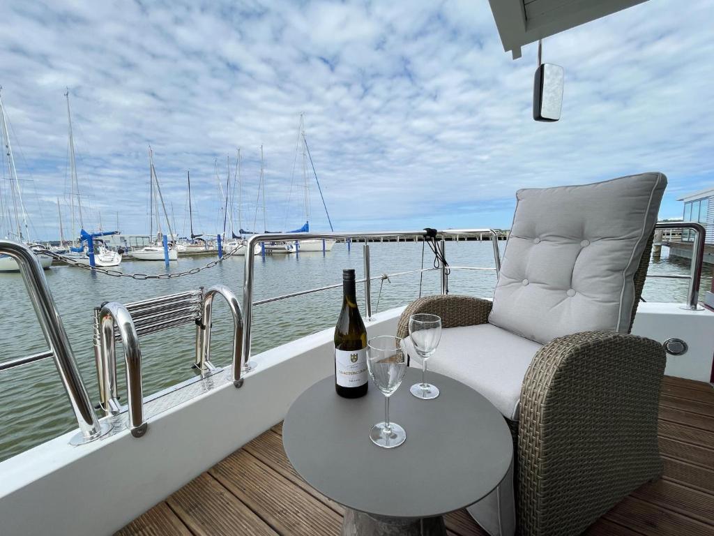 a table with a bottle of wine and two glasses on a boat at Hausboot Paula mit Reisekajak in Ribnitz-Damgarten in Ribnitz-Damgarten