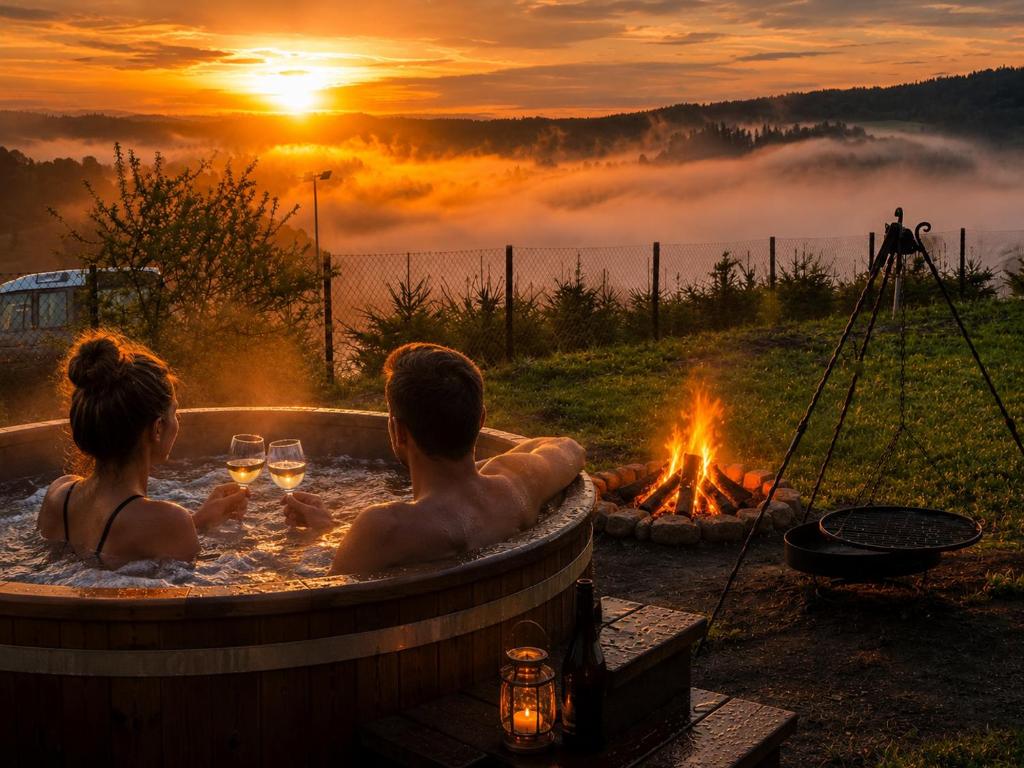 a man and woman sitting in a hot tub next to a fire at Chaty Jak Dawniej 787-330-207 in Wołkowyja