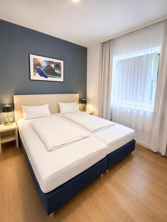 a large white bed in a bedroom with a window at Hotel Mainbrücke in Kitzingen