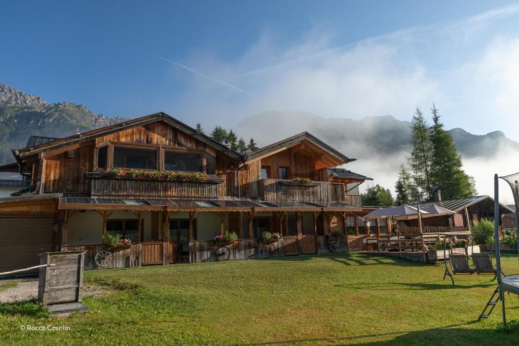 a large wooden house with mountains in the background at B&B IL Nido in Sappada