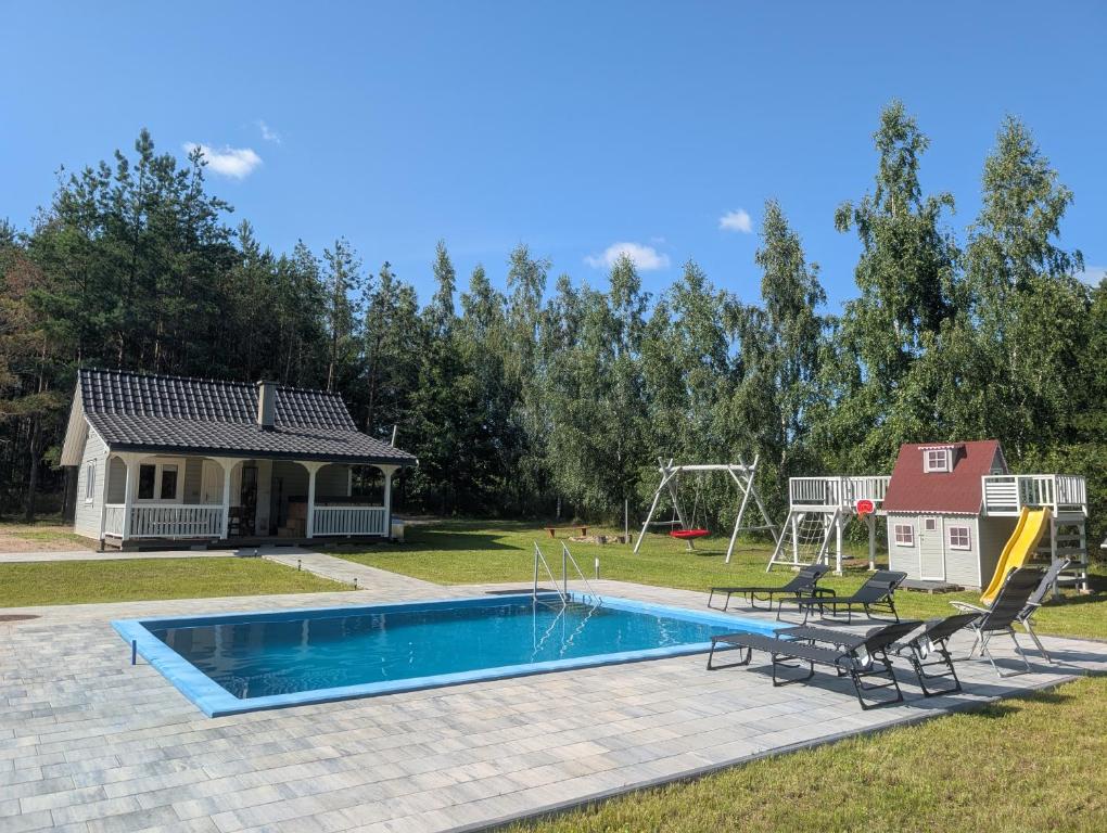a swimming pool with two chairs and a playground at Chill House Sedranki in Olecko